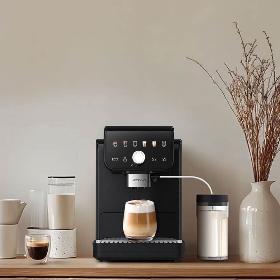Jetinno JL05B preta sobre bancada de madeira, com cappuccino na bandeja e jarra de leite conectada ao espumador